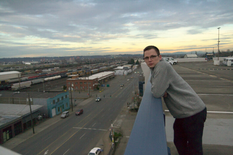 Portrait of Aquarium Drinker leaning against a railing outside